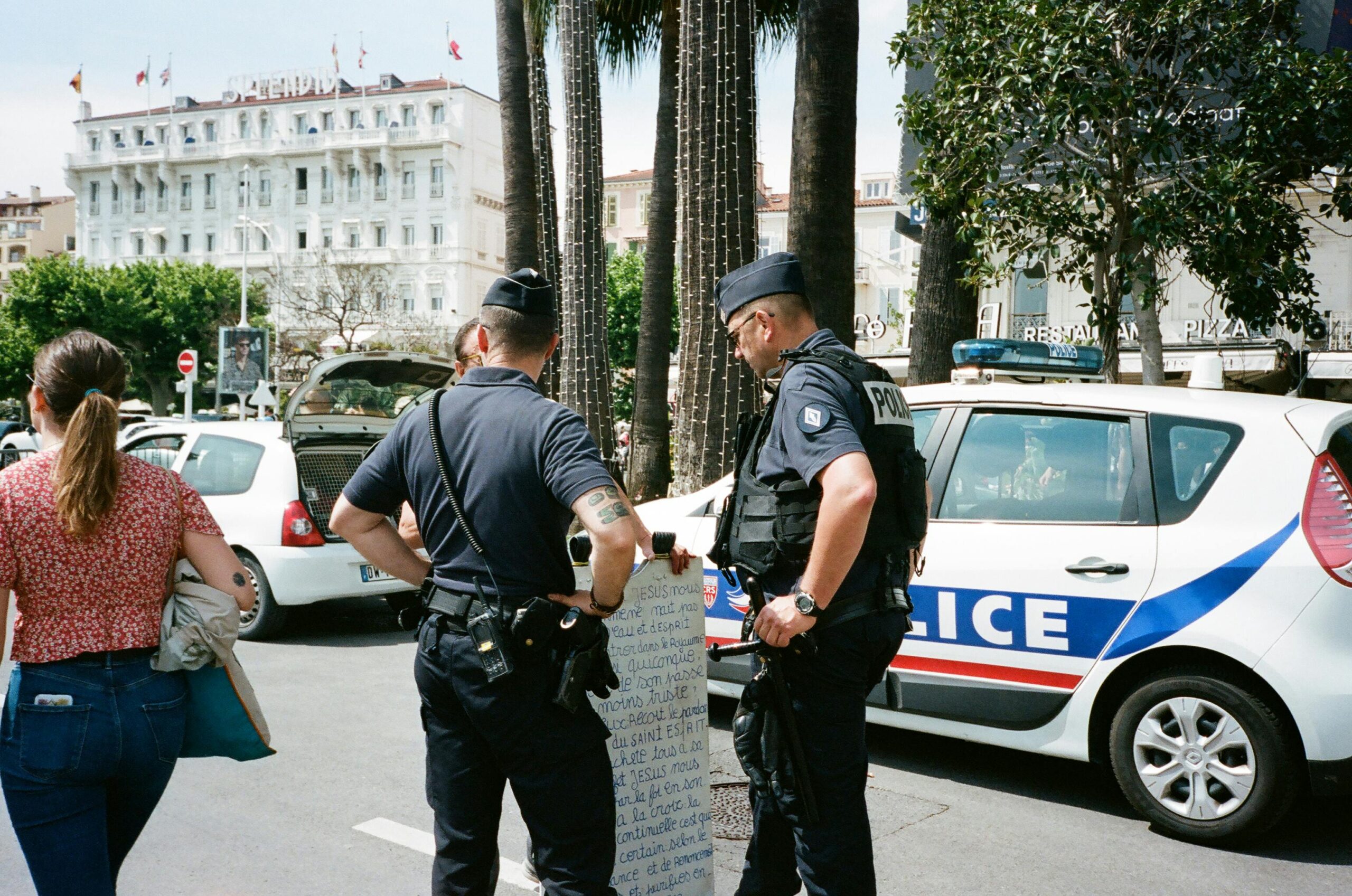 Police officers and a civilian interact near a police car on a busy city street.